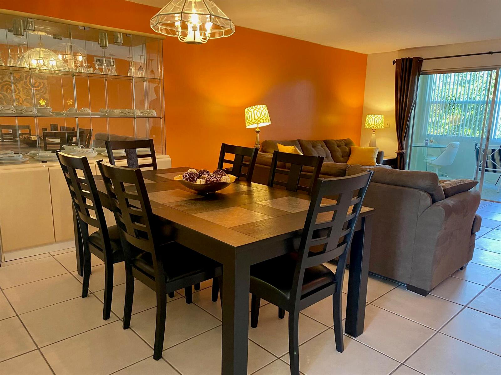 A dining area with a dark wood table and chairs sits before an orange wall — 2615 NE 3rd Court # 302, Boynton Beach FL 33435, BOYNTON BEACH, FL