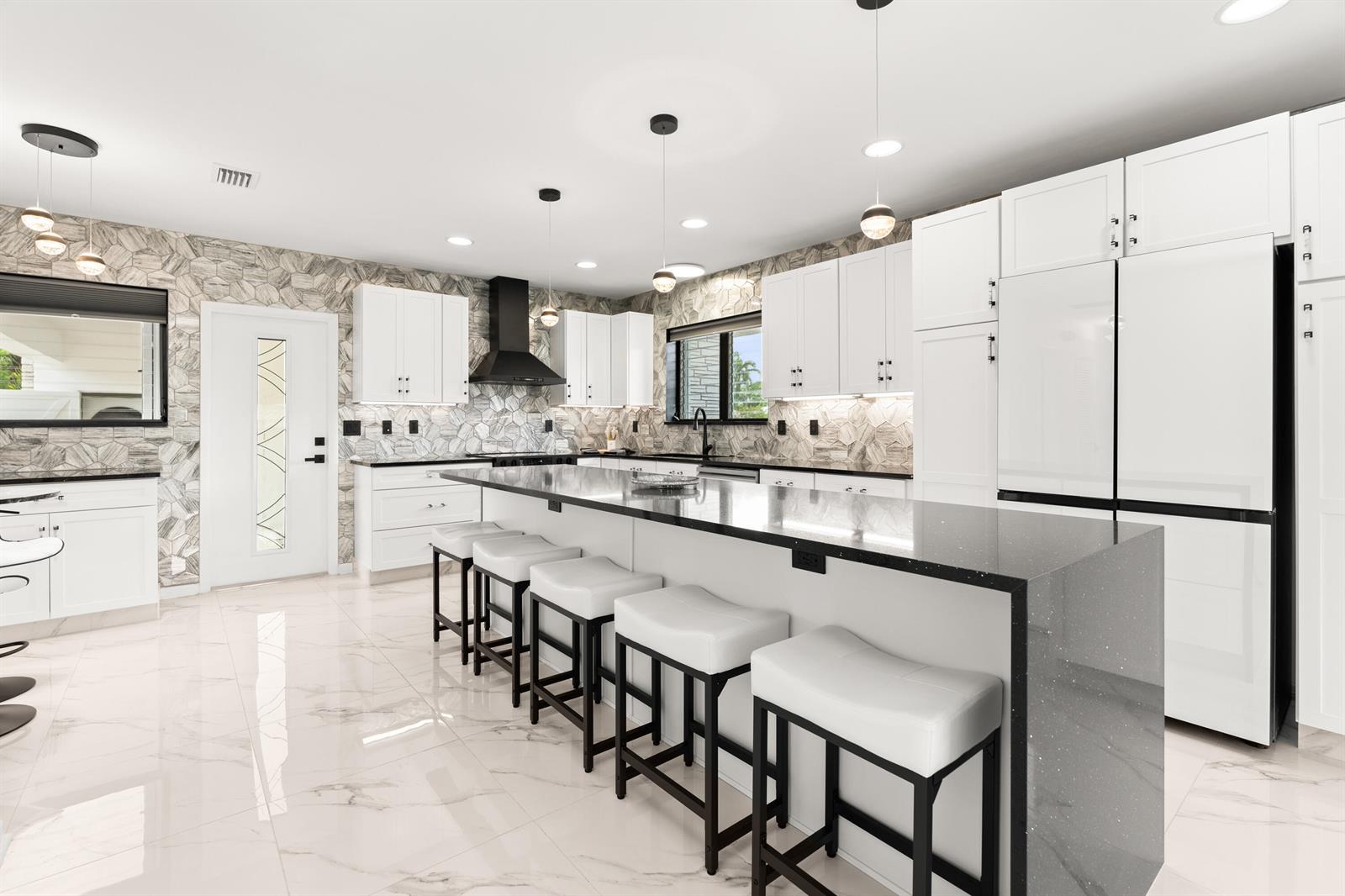 A modern kitchen features white cabinets, a large island with bar seating, and marble flooring — 1428 N M Street, Lake Worth FL 33460, LAKE WORTH, FL