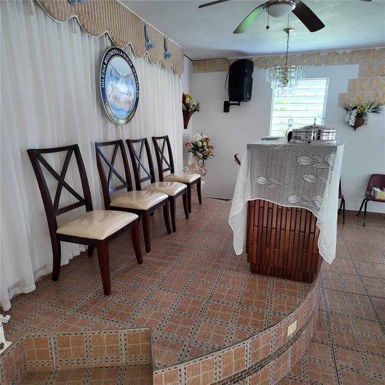 A raised platform with tiled flooring features four wooden chairs and a covered podium — Carr 157 KM 23.2 INT BO. BARROS, OROCOVIS, PR