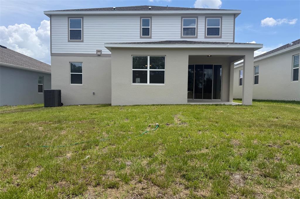 The rear exterior of a two-story house features a covered patio and a grassy yard — 2029 HEART LAKE DRIVE, GROVELAND, FL