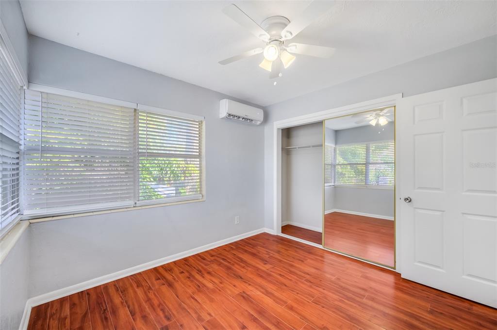 A bedroom with light gray walls, wood-look flooring, a ceiling fan, and a mirrored closet — 1070 S CLEARVIEW AVE UNIT 10, TAMPA, FL