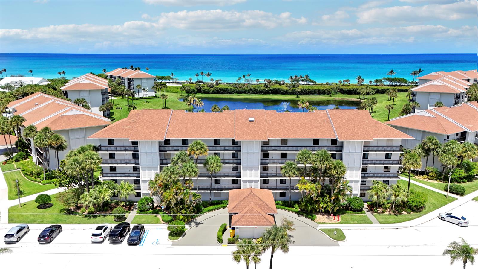 An aerial view shows a multi-story apartment building with a brown roof near the ocean — 401 S Seas Drive # 203, Jupiter FL 33477, JUPITER, FL
