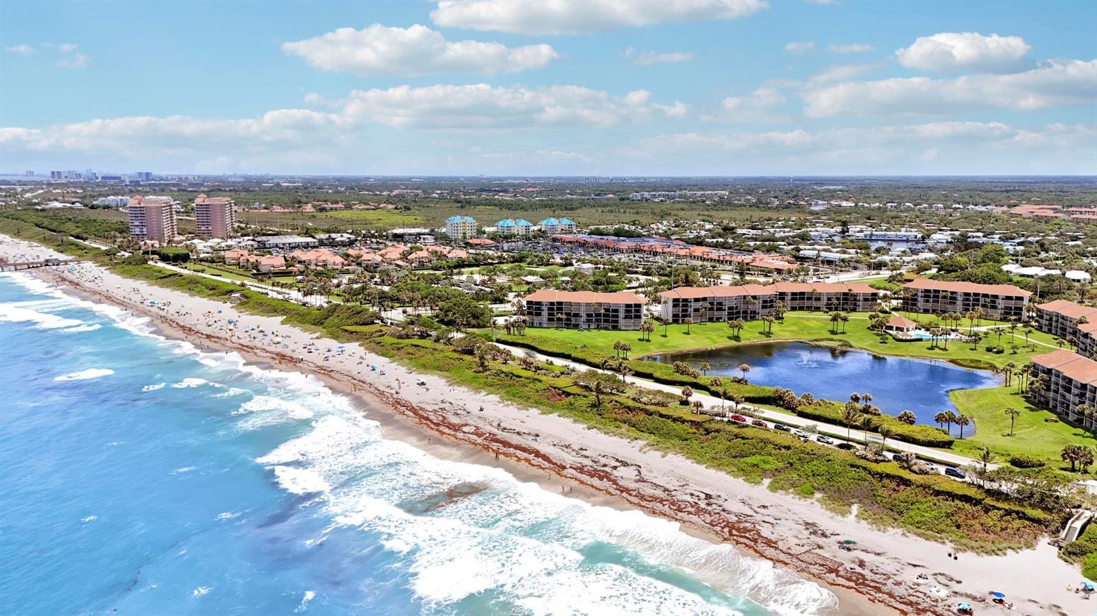 An aerial view shows a beach with multi-story residential buildings and a pond nearby — 401 S Seas Drive # 203, Jupiter FL 33477, JUPITER, FL