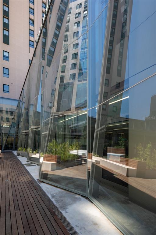 A wooden deck sits beside a modern building with angled glass walls and interior seating — 290 RUA DE SANTOS POUSADA, PORTO, OC