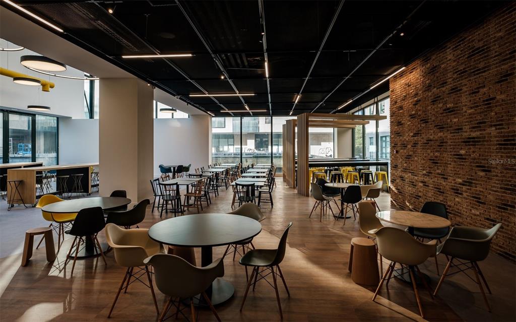A modern office breakroom features round tables, colorful chairs, and an exposed brick wall — 290 RUA DE SANTOS POUSADA, PORTO, OC