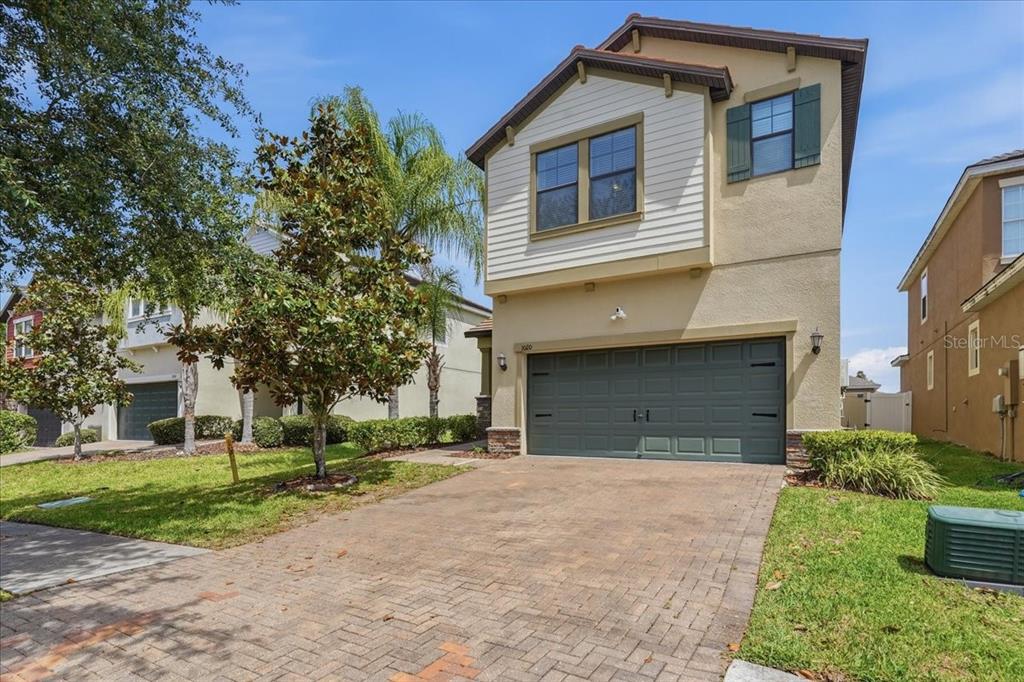 A two-story house with a beige stucco exterior, a dark green garage, and a brick driveway — 1020 OLIVETO VERDI COURT, BRANDON, FL