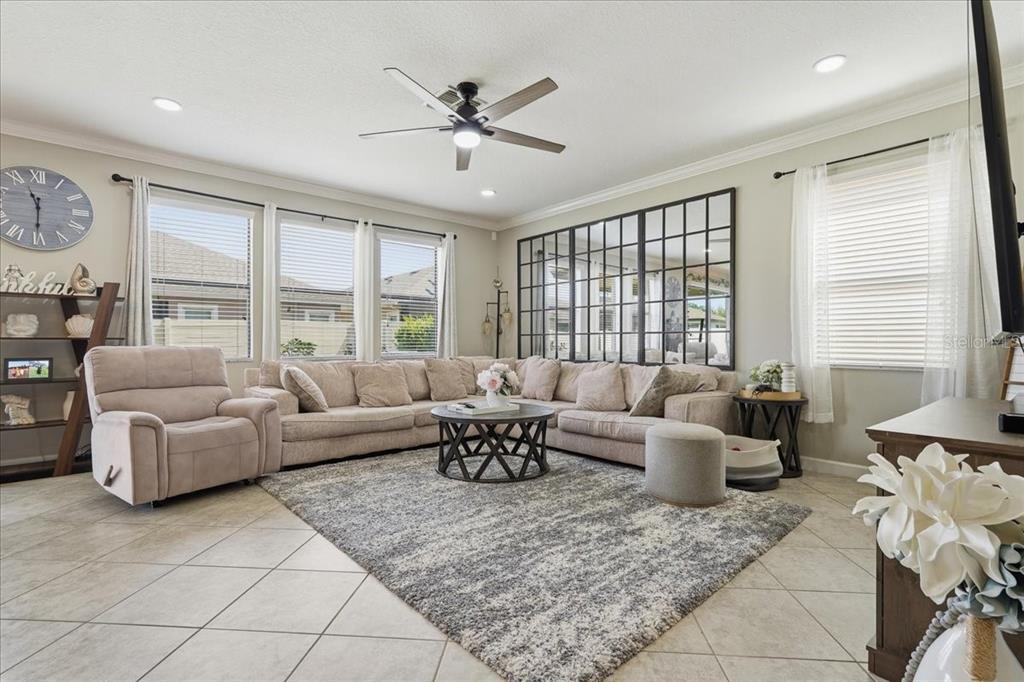 A living room features a large sectional sofa, a gray area rug, and a wall mirror — 1020 OLIVETO VERDI COURT, BRANDON, FL