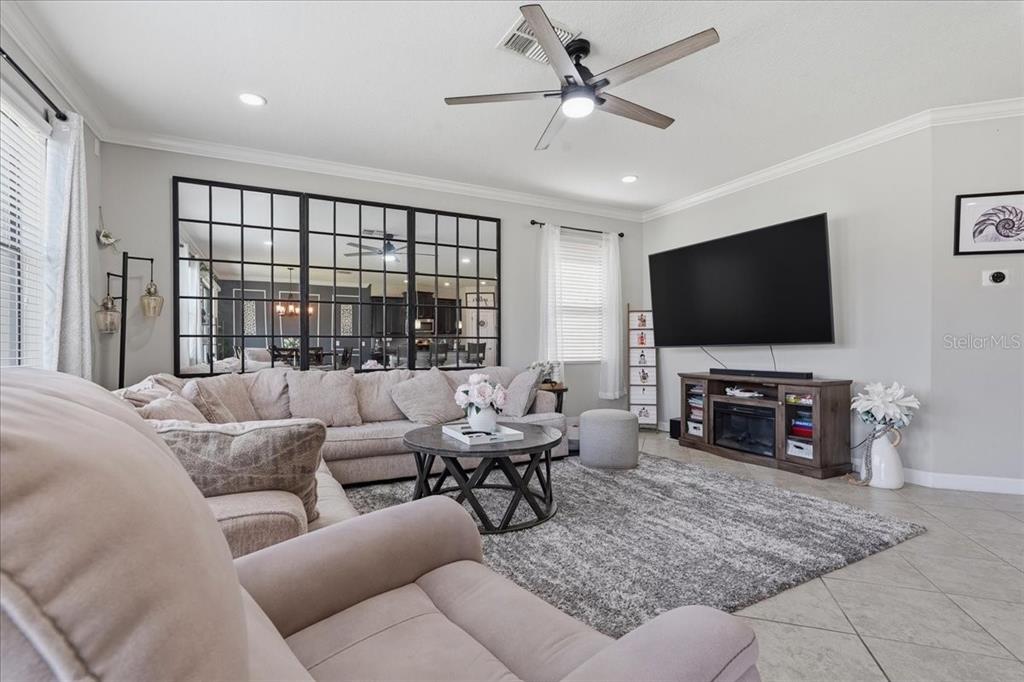 A living room features a large sectional sofa, a grid-paneled mirror, and a wall-mounted television — 1020 OLIVETO VERDI COURT, BRANDON, FL