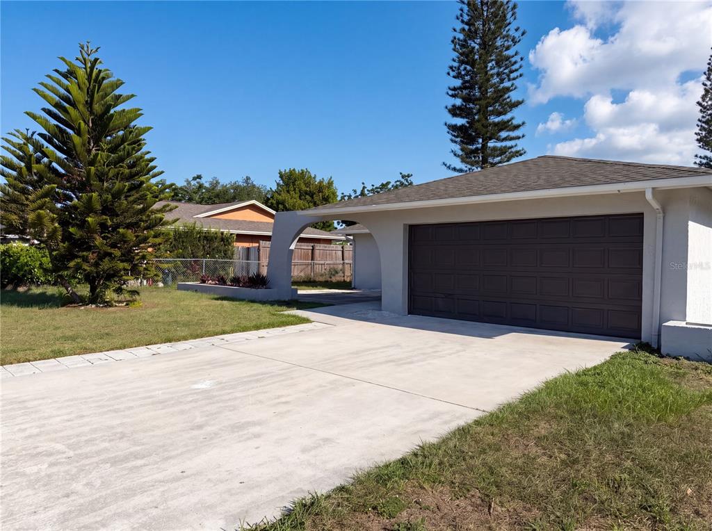 A concrete driveway leads to a two-car garage with a decorative arched entryway — 607 33RD AVENUE DRIVE E, BRADENTON, FL