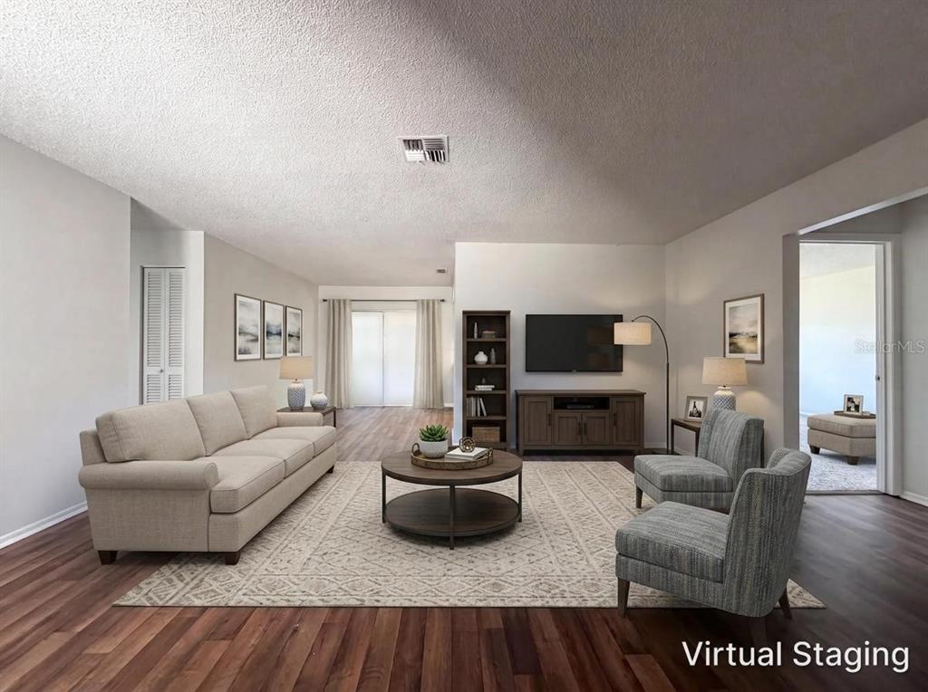 A virtually staged living room features a beige sofa, two armchairs, and wood-look flooring — 607 33RD AVENUE DRIVE E, BRADENTON, FL