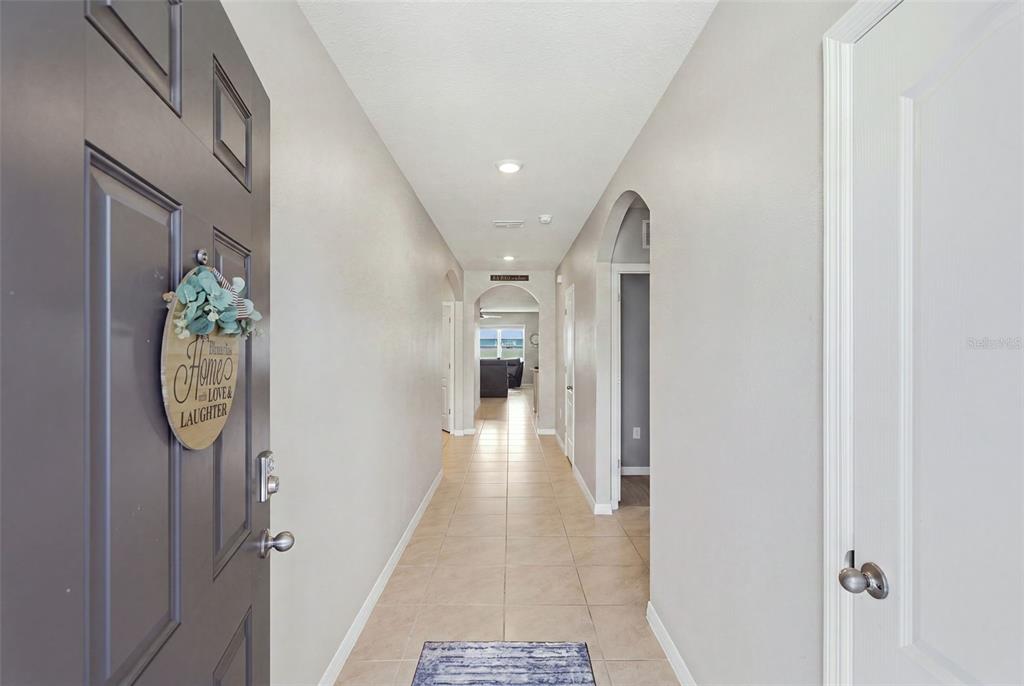 A tiled entryway hallway leads to an open living area with light gray walls — 2561 HARMONIA HAMMOCK RD, HARMONY, FL