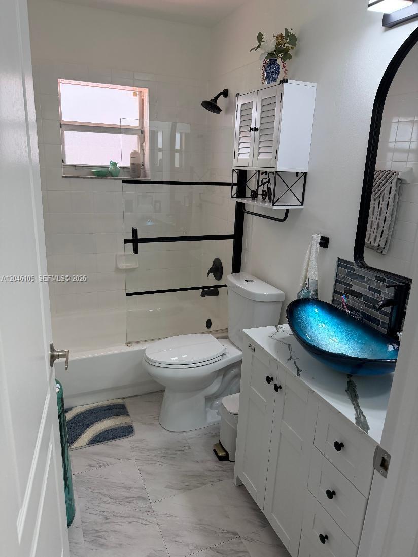 A bathroom features a blue glass vessel sink, white vanity, and a tub-shower combination — 19554 NW 79th Pl, Hialeah FL 33015, HIALEAH, FL