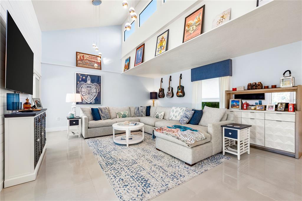 A living room features a large sectional sofa, a patterned rug, and guitars on the wall — 2500 MONTEREY STREET, SARASOTA, FL