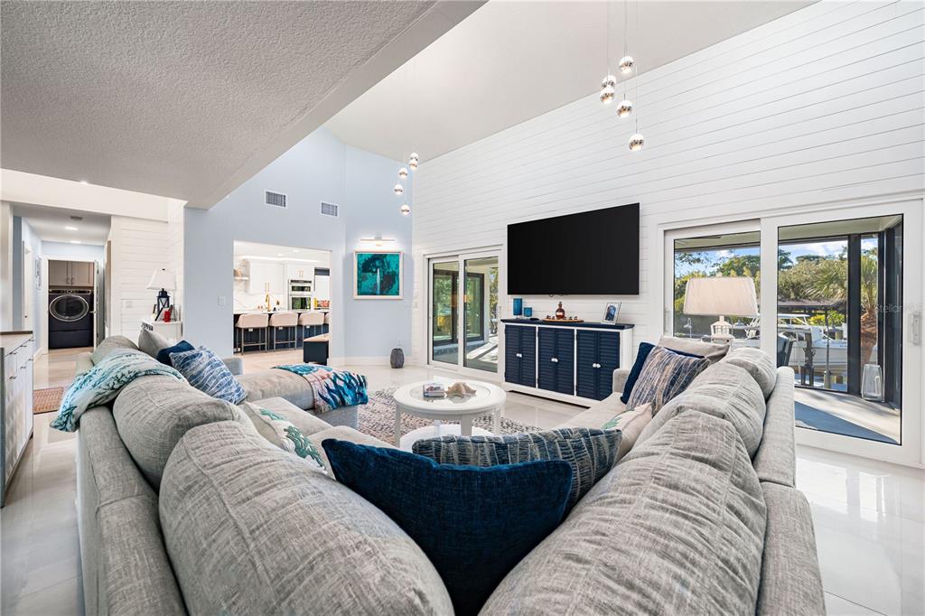 A spacious living room features vaulted ceilings, white shiplap walls, and a large sectional sofa — 2500 MONTEREY STREET, SARASOTA, FL