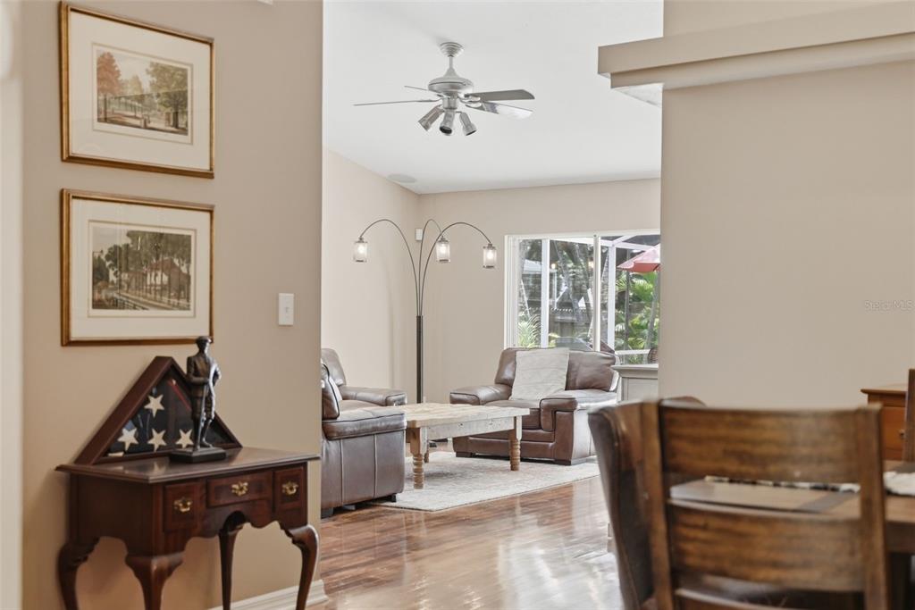 A view from a dining area into a living room with leather furniture and flooring — 4989 162ND AVENUE N, CLEARWATER, FL