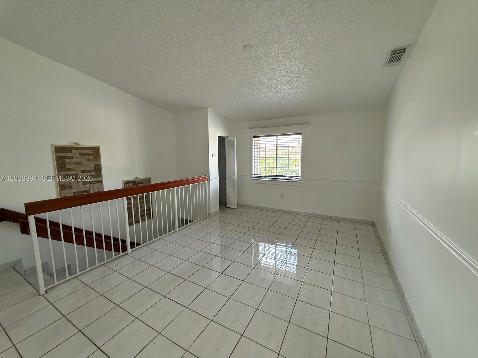 A tiled loft area features a wooden staircase railing and a window with blinds — 2212 W 74th St # 28, Hialeah FL 33016, HIALEAH, FL