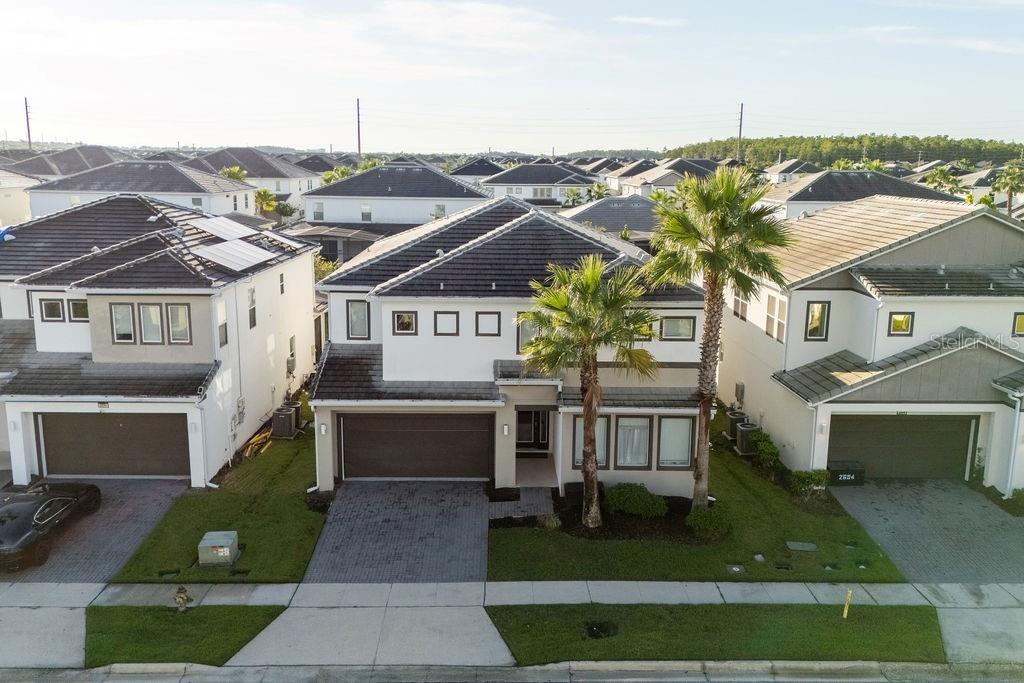 An aerial view of a two-story suburban house with a dark tiled roof and driveway — 2692 CALISTOGA AVENUE, KISSIMMEE, FL