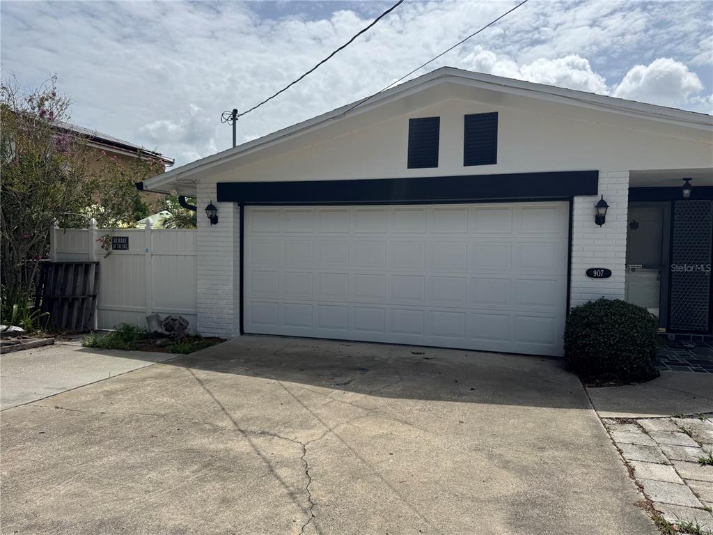 A white brick house features a two-car garage, black trim, and a concrete driveway — 907 S FLORIDA AVENUE, TARPON SPRINGS, FL