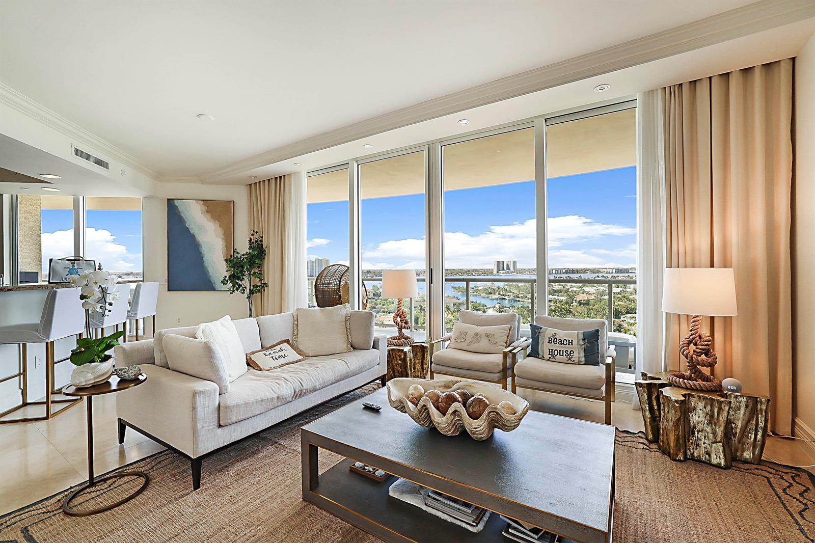 A living room features a sofa, two armchairs, a coffee table, and floor-to-ceiling windows — 2700 N Ocean Drive # 1006b, Riviera Beach FL 33404, RIVIERA BEACH, FL