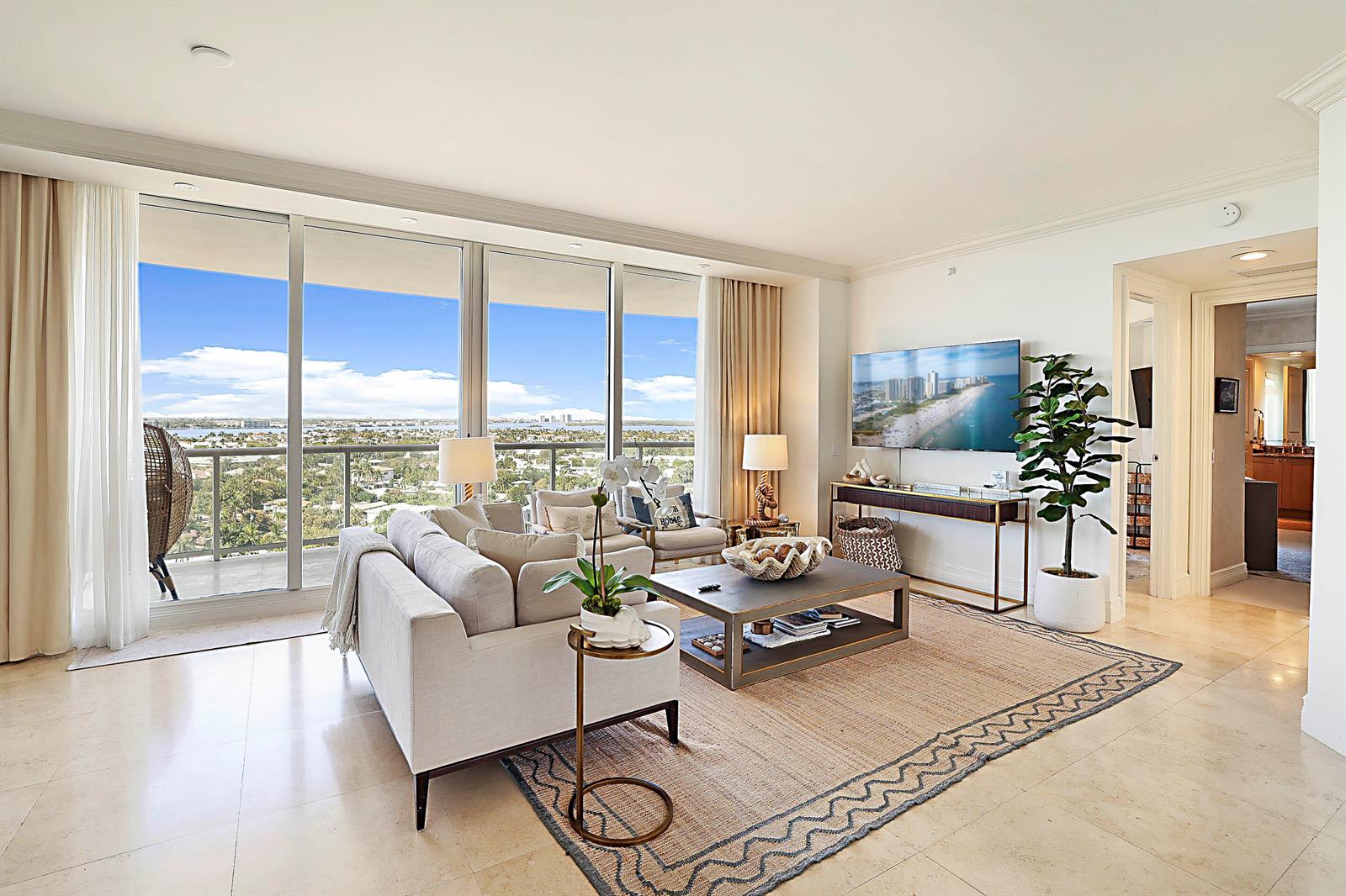 A bright living room features a sofa, coffee table, and floor-to-ceiling windows with coastal views — 2700 N Ocean Drive # 1006b, Riviera Beach FL 33404, RIVIERA BEACH, FL