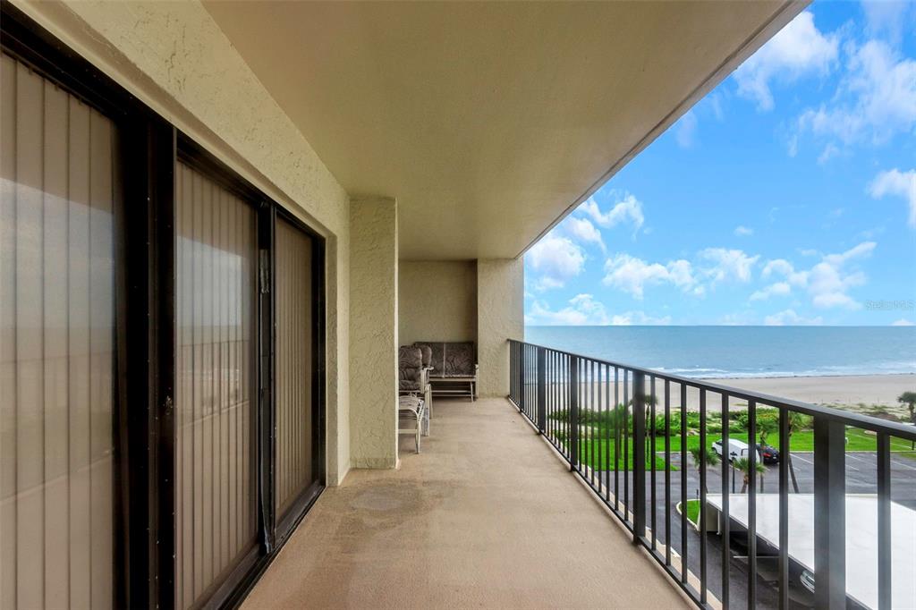A covered balcony overlooks the ocean with a black metal railing and sliding glass doors — 1480 GULF BOULEVARD UNIT 506, CLEARWATER BEACH, FL