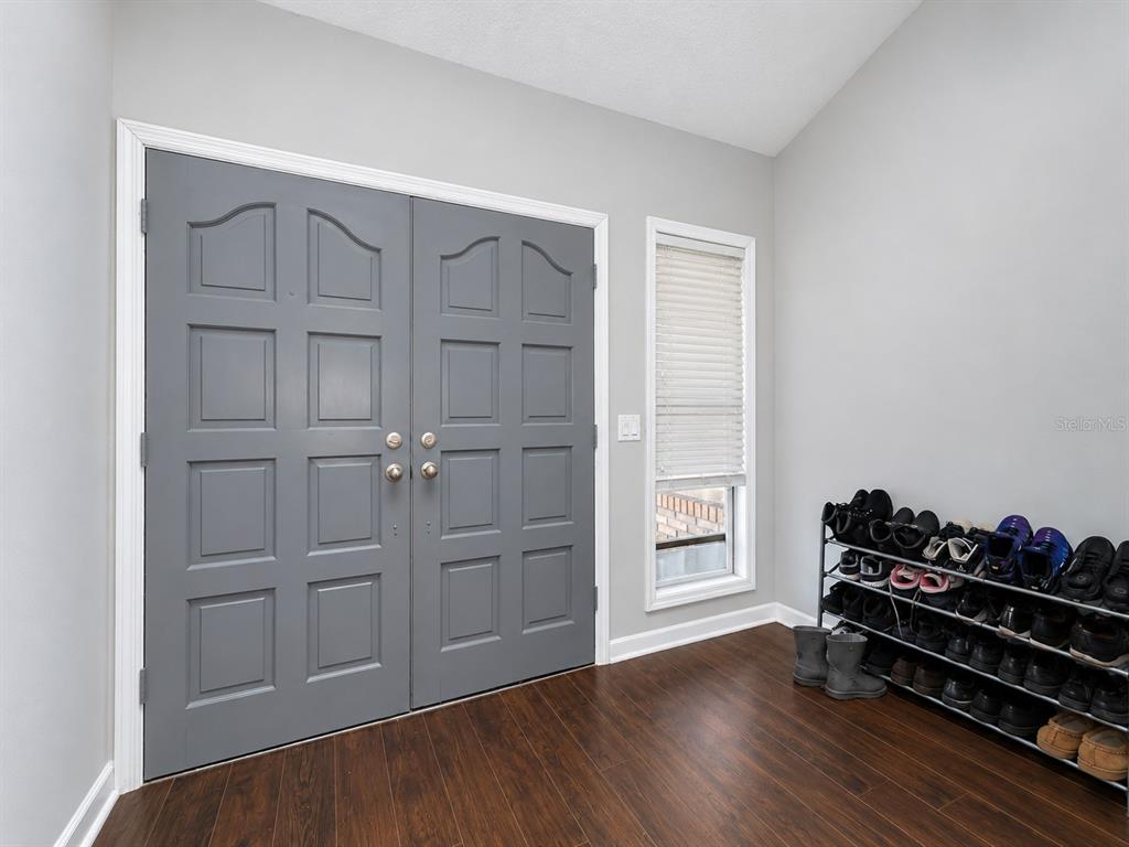 An entryway features gray double doors, dark wood flooring, and a metal shoe rack — 290 GLENEAGLES DRIVE, ORANGE PARK, FL