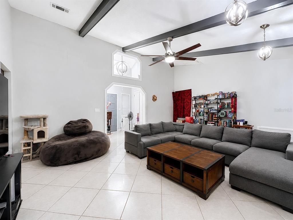 A living room features a large gray sectional, a beanbag chair, and exposed ceiling beams — 290 GLENEAGLES DRIVE, ORANGE PARK, FL