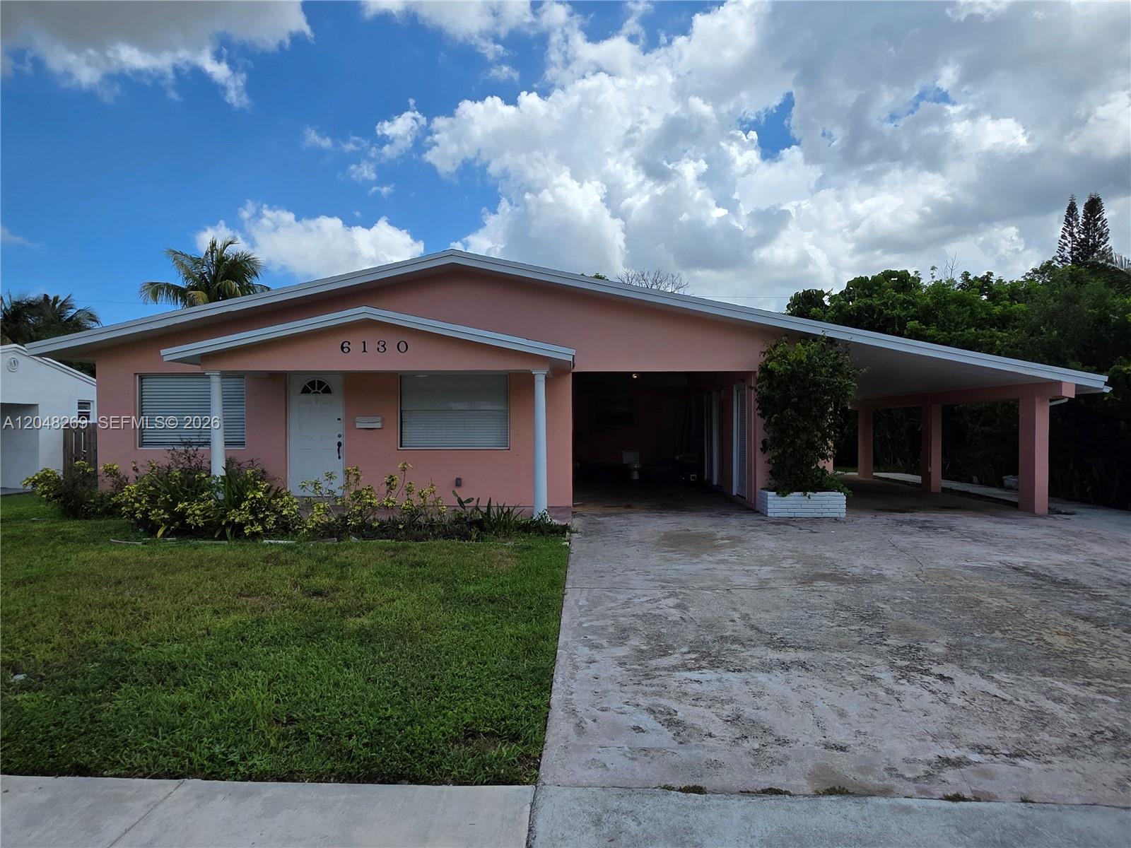 A single-story pink house features a front lawn, a concrete driveway, and a covered carport — 6130 Funston St, Hollywood FL 33023, HOLLYWOOD, FL