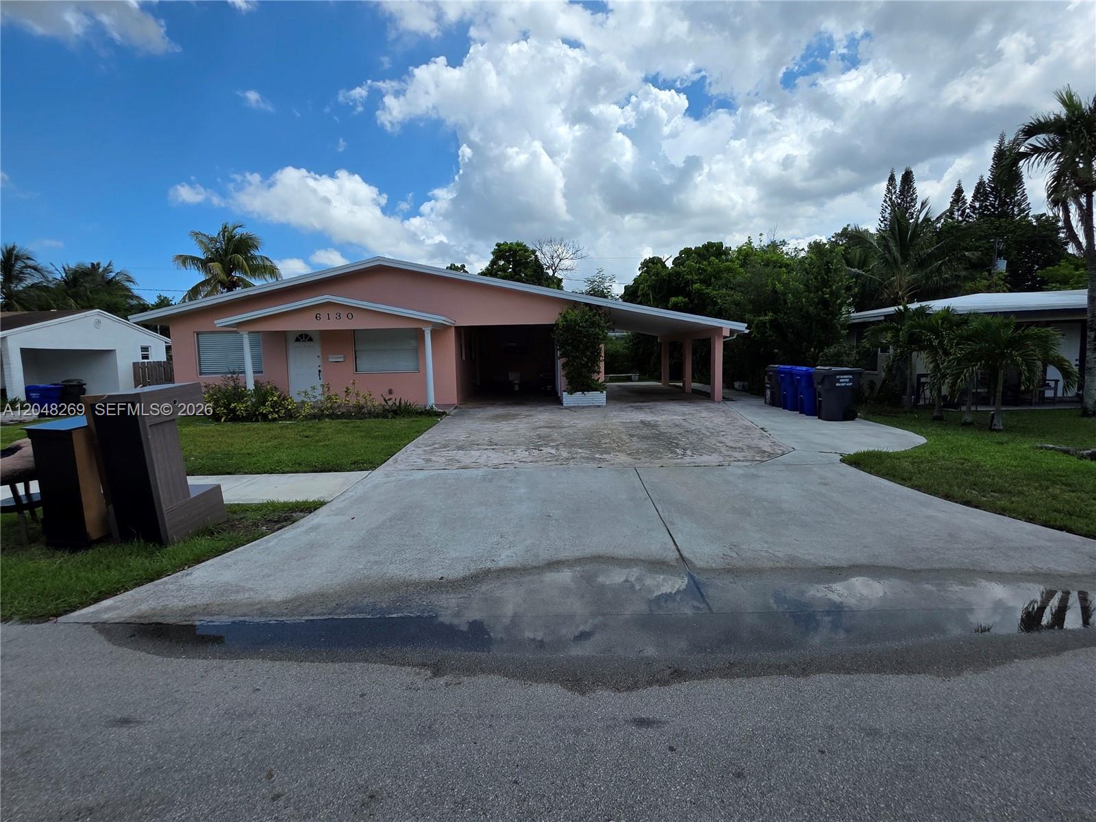 A single-story pink house features a concrete driveway, a carport, and a grassy front yard — 6130 Funston St, Hollywood FL 33023, HOLLYWOOD, FL