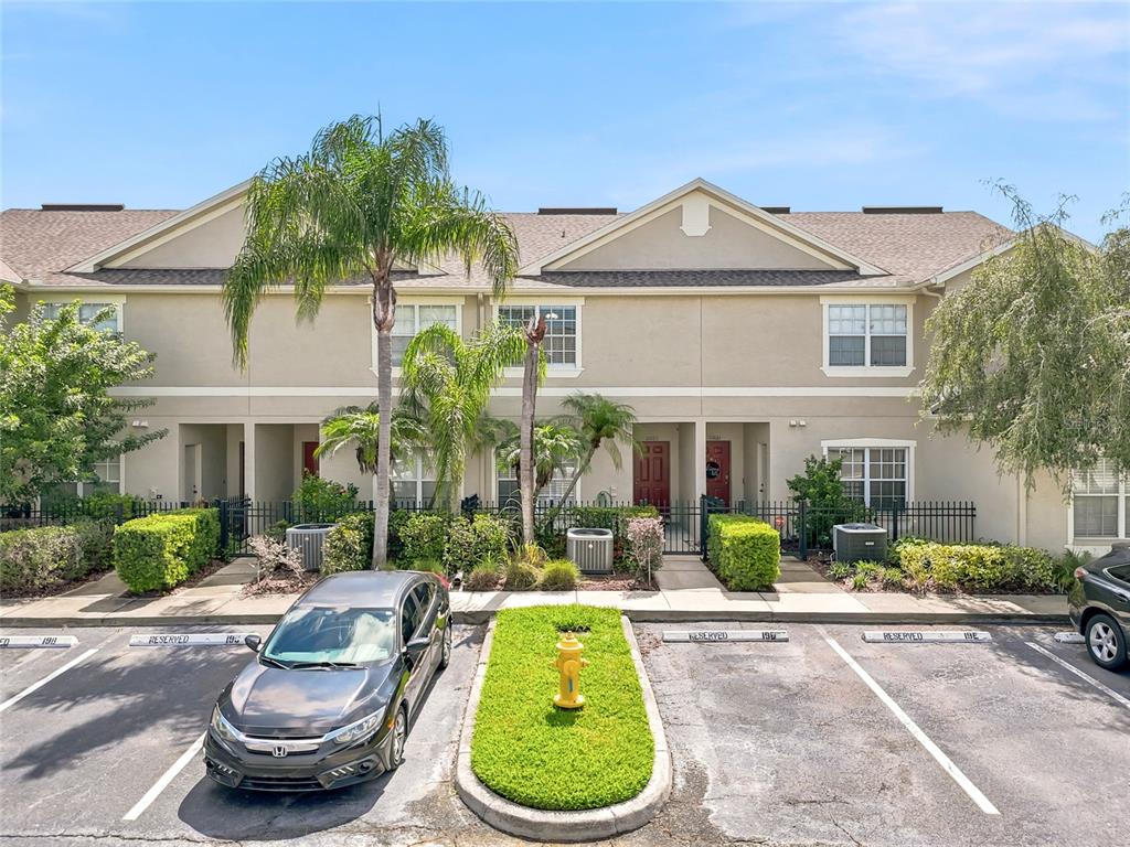 A row of townhomes features tan stucco siding, dark roofs, and reserved parking spaces — 11023 WINTER CREST DRIVE, RIVERVIEW, FL