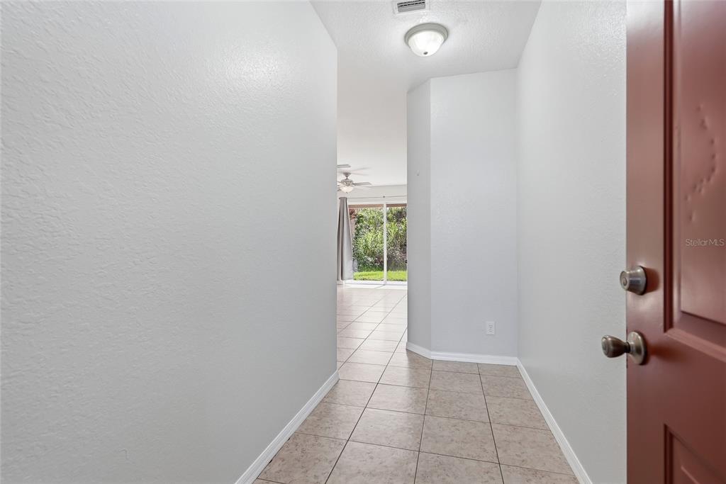 An entryway with light-colored tile flooring leads toward a living area with sliding glass doors — 11023 WINTER CREST DRIVE, RIVERVIEW, FL