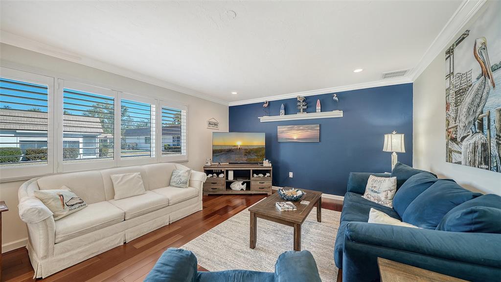 A living room features a white sofa, a blue sofa, and a dark blue accent wall — 2721 RIVERBLUFF PLACE UNIT V-50, SARASOTA, FL