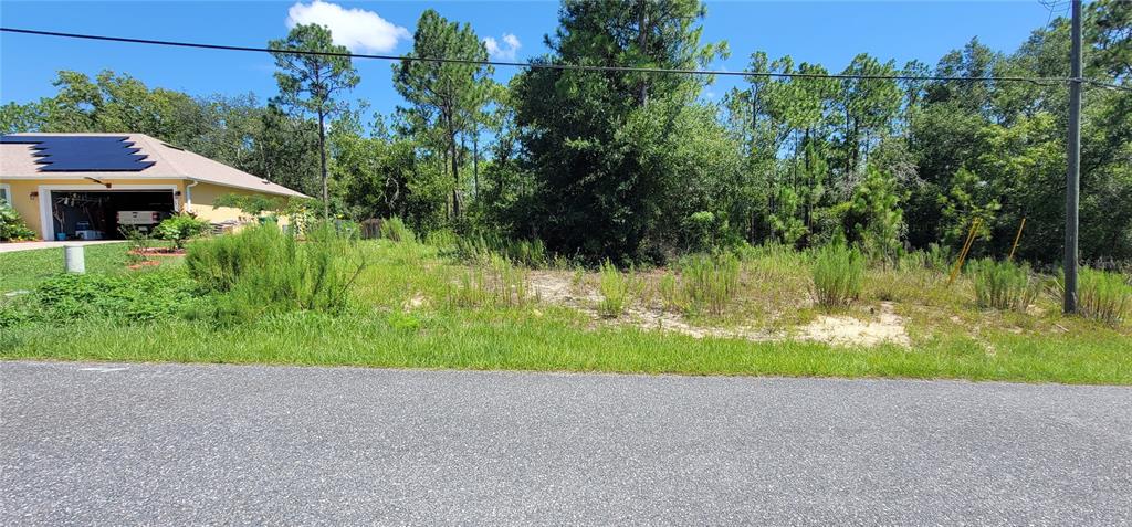 A vacant, grassy residential lot sits next to a house with solar panels — 7163 N GLENRIDGE CIRCLE, CITRUS SPRINGS, FL