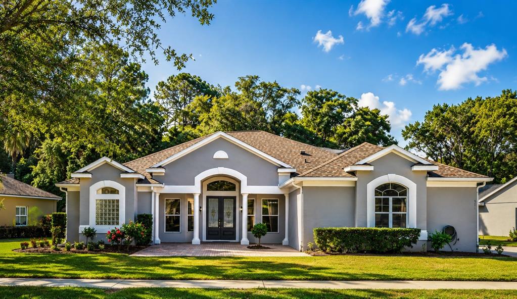 A single-story gray house with a white-trimmed arched entryway and a shingled roof — 571 MASALO PLACE, LAKE MARY, FL