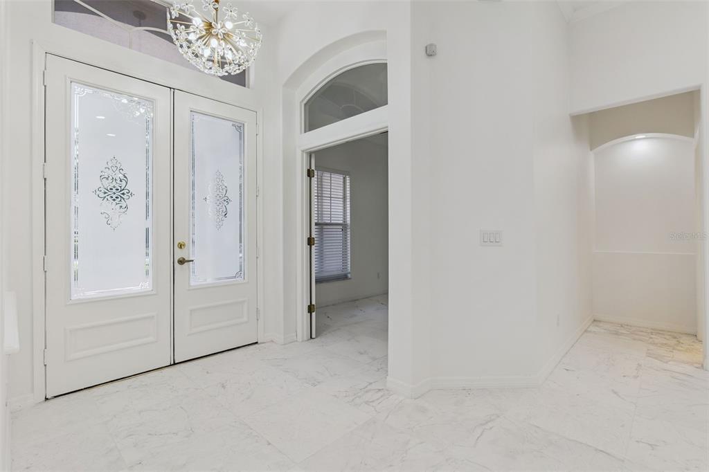 A bright entryway features white marble floors, double front doors, and a decorative chandelier — 571 MASALO PLACE, LAKE MARY, FL