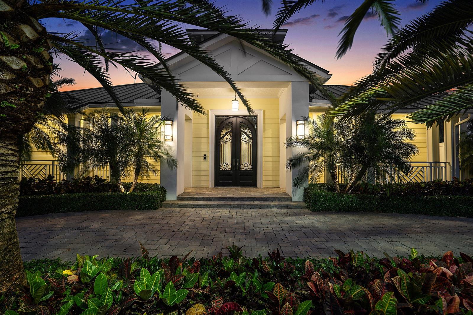 A yellow house with a dark arched double door entrance and palm trees at dusk — 201 NE 3rd Court, Boca Raton FL 33432, BOCA RATON, FL