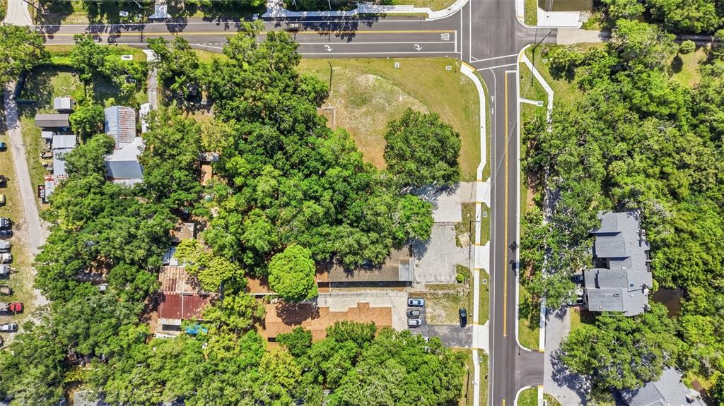 An aerial view shows a wooded property with a building, parking area, and adjacent roads — 2886 WHITNEY ROAD, CLEARWATER, FL