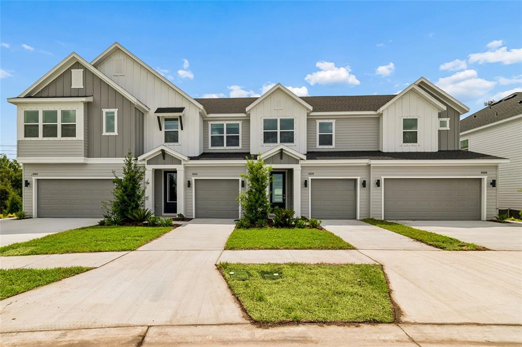 A multi-unit residential building with gray siding, multiple garage doors, and a shared driveway — 6406 JENSEN VIEW AVENUE, APOLLO BEACH, FL