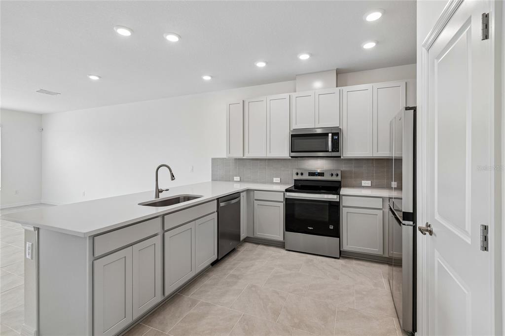 A modern kitchen features light gray cabinets, stainless steel appliances, and a large island — 6406 JENSEN VIEW AVENUE, APOLLO BEACH, FL
