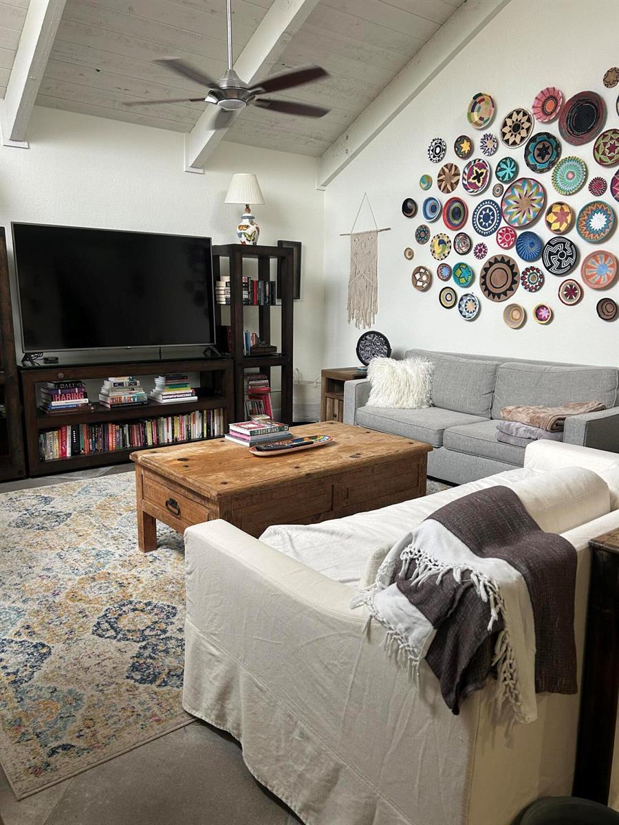 A living room features a large TV, two sofas, a coffee table, and a basket wall — 1605 S Us Hwy 1 # H, Jupiter FL 33477, JUPITER, FL