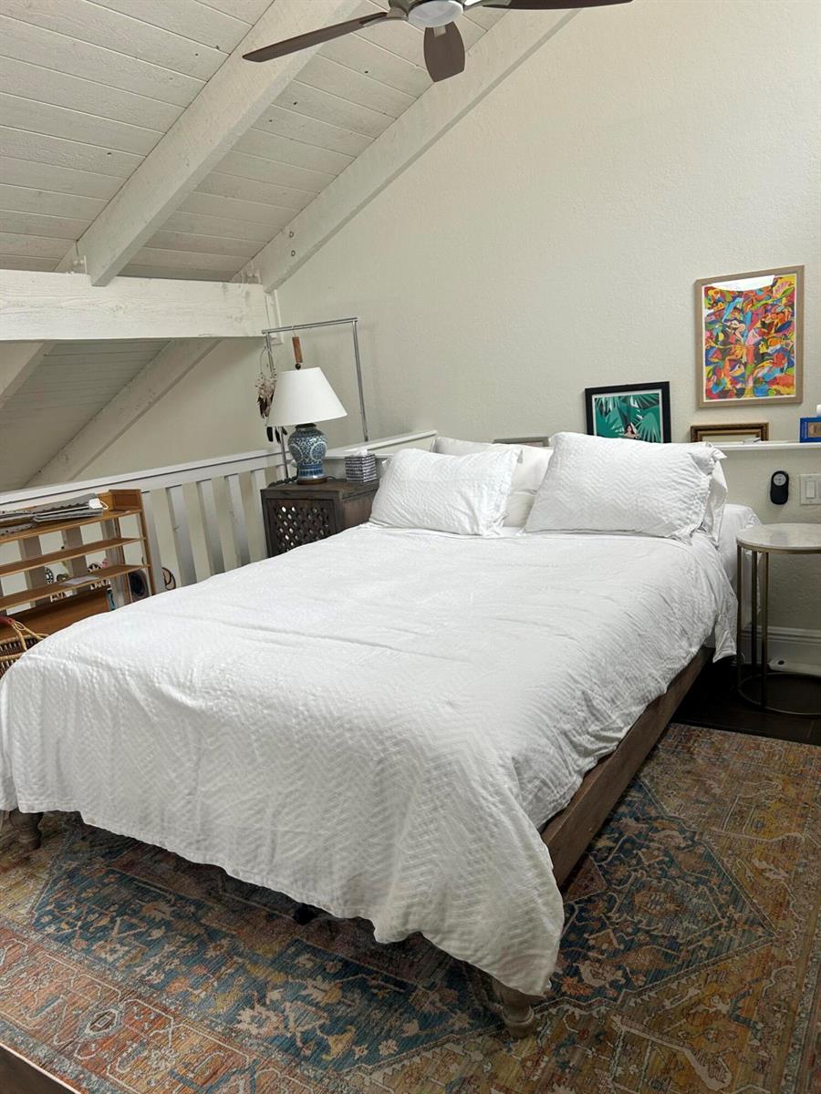 A bedroom with a white bed, patterned rug, and vaulted ceiling in a loft space — 1605 S Us Hwy 1 # H, Jupiter FL 33477, JUPITER, FL
