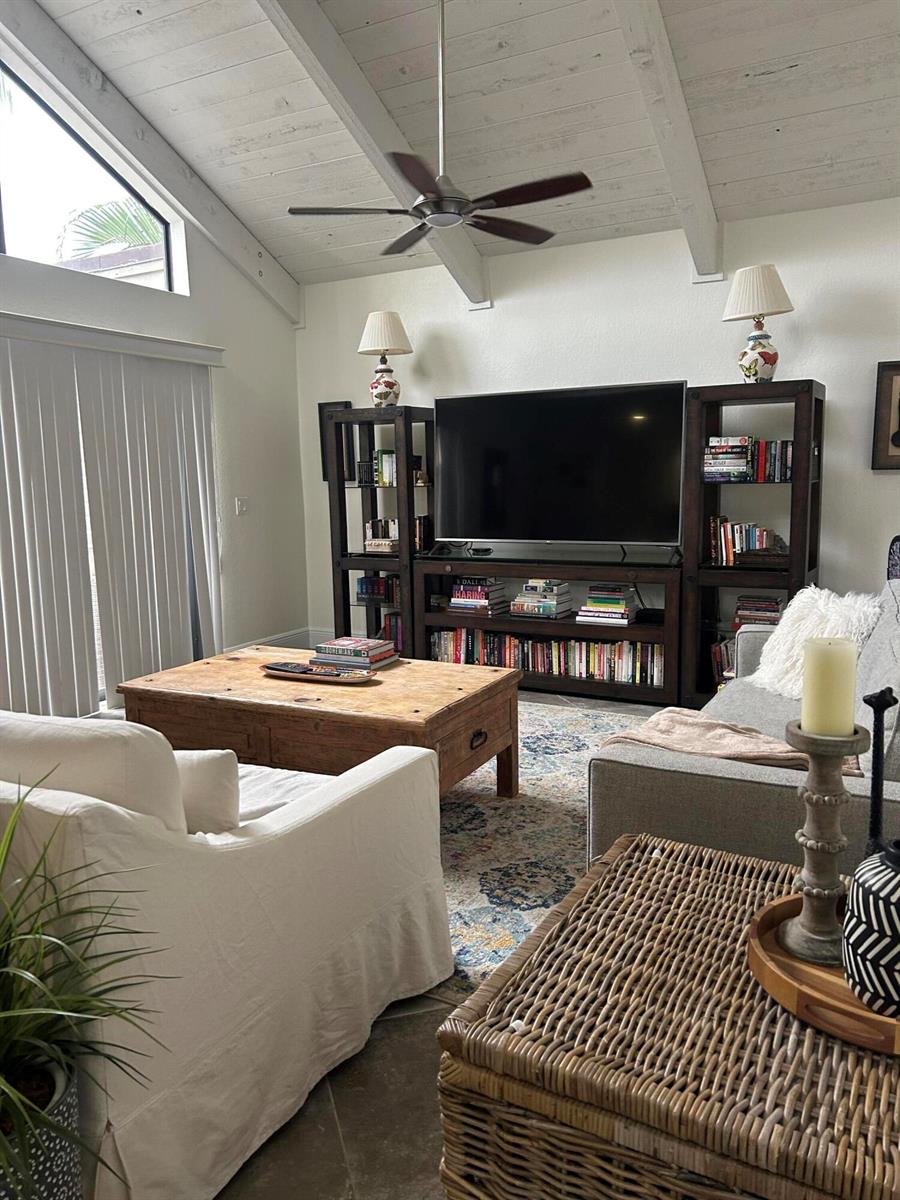A living room features a vaulted ceiling, a large television unit, and a wooden coffee table — 1605 S Us Hwy 1 # H, Jupiter FL 33477, JUPITER, FL