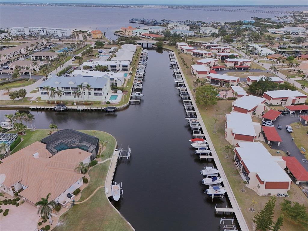 An aerial view shows a canal lined with residential buildings and numerous docked boats — 311 GARVIN STREET UNIT 411B, PUNTA GORDA, FL