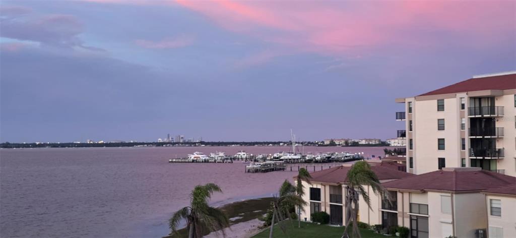 An elevated exterior view of a waterfront apartment building overlooking a marina at sunset — 6177 SUN BOULEVARD UNIT 401, ST PETERSBURG, FL