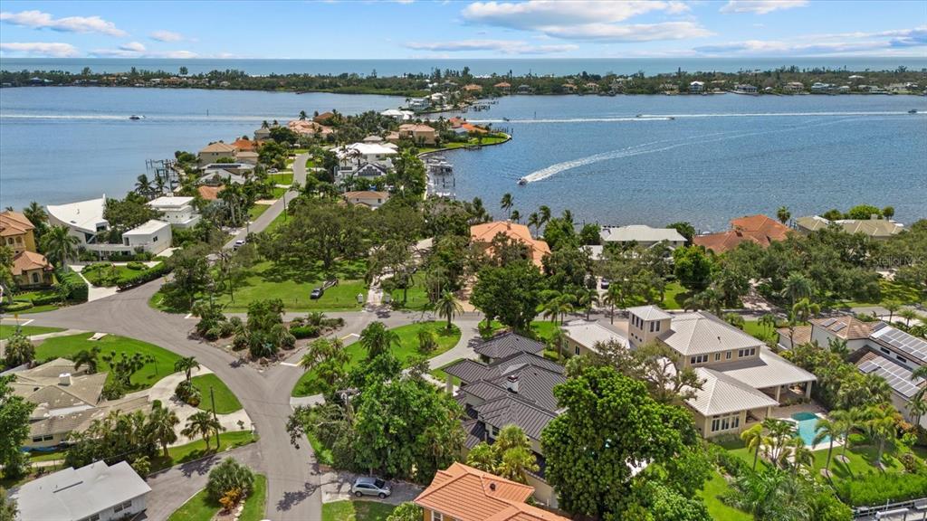 An aerial view of a coastal neighborhood featuring waterfront homes, lush trees, and a bay — 1707 CARIBBEAN DRIVE, SARASOTA, FL
