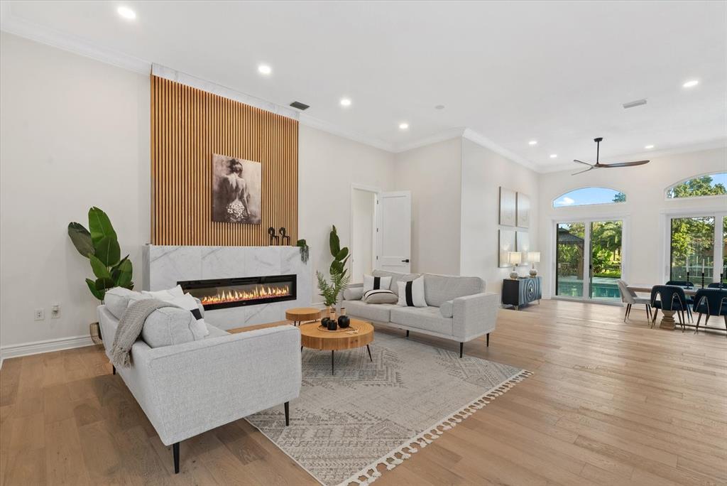 A bright living room features a marble fireplace with wood slat wall accents and flooring — 1707 CARIBBEAN DRIVE, SARASOTA, FL