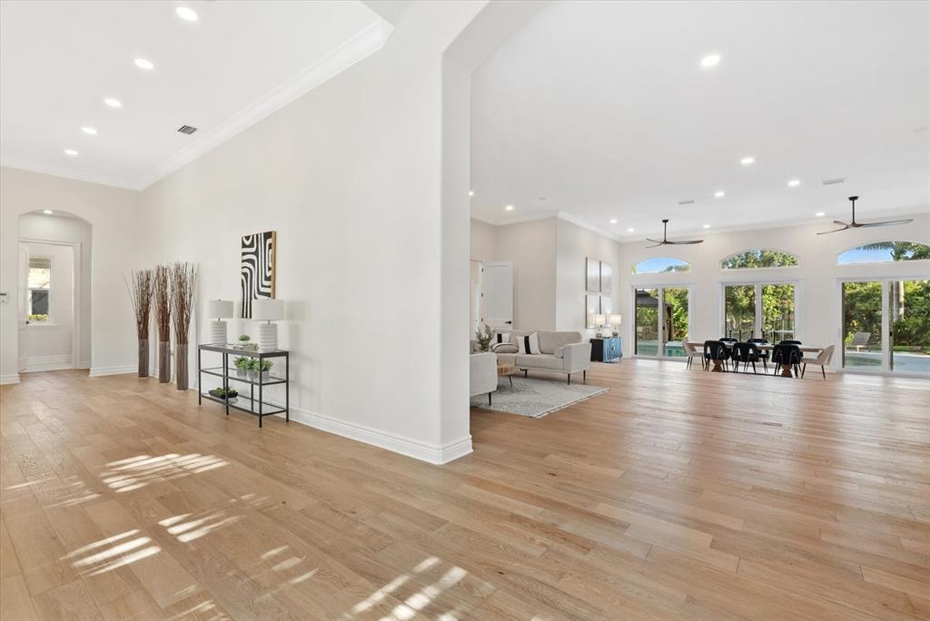 A spacious, open-concept living and dining area features light hardwood floors and large glass doors — 1707 CARIBBEAN DRIVE, SARASOTA, FL