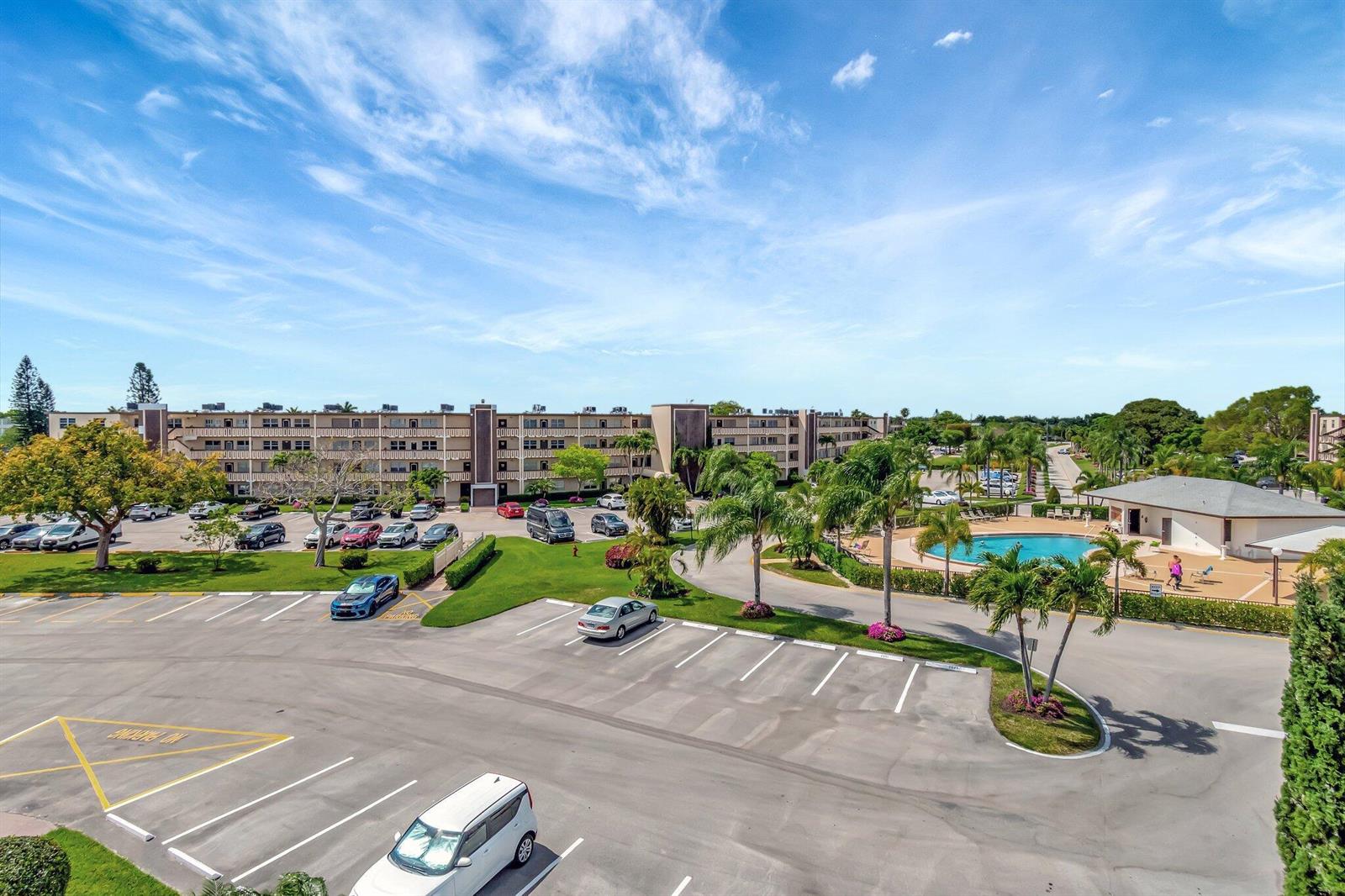An aerial view of an apartment complex featuring a parking lot, swimming pool, and landscaping — 4049 Wolverton C, Boca Raton FL 33434, BOCA RATON, FL