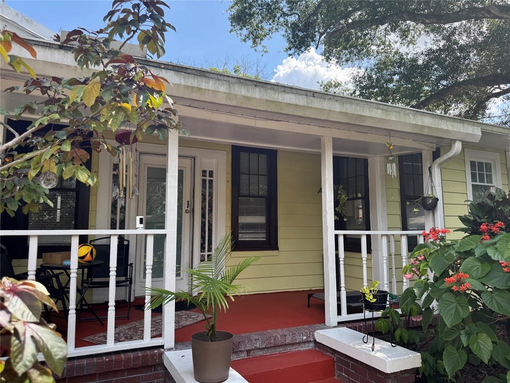 A front porch with a red floor, white railings, and yellow siding on a house — 6408 N HIGHLAND AVENUE, TAMPA, FL