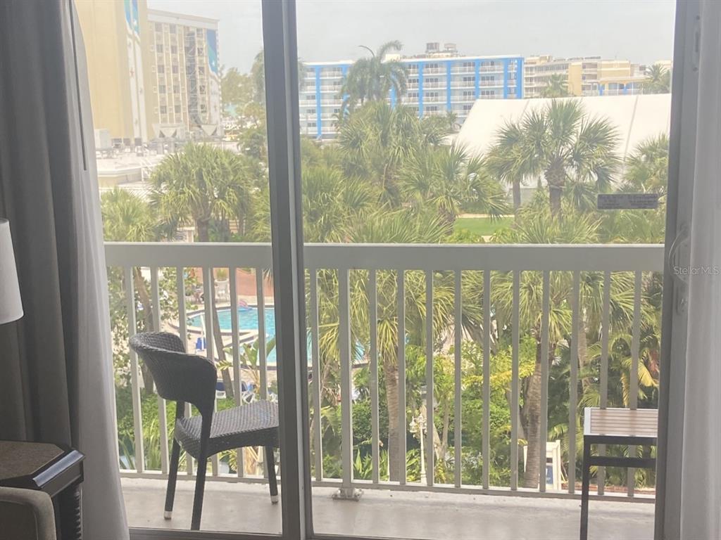 A balcony view features a swimming pool, palm trees, and surrounding hotel buildings — 5500 GULF BOULEVARD UNIT 4246, ST PETE BEACH, FL